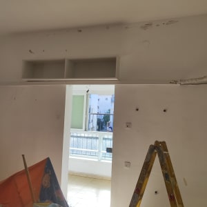 סולם צהוב ליד קיר עם חורים ותיקוני צבע