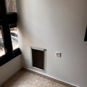 פתח בקיר עם דלת קטנה, שקע חשמל ורצפת אריחים