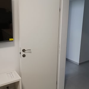 דלת לבנה עם ידית מתכת כסופה פתוחה למחצה