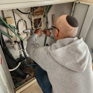 אדם מתקן חוטים בארון תקשורת