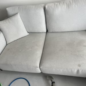 ספה עם כתמים וכלי ניקוי על הרצפה