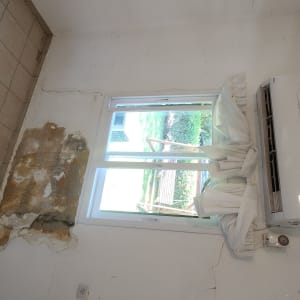 קיר עם סדקים ותיקונים ליד חלון ומזגן