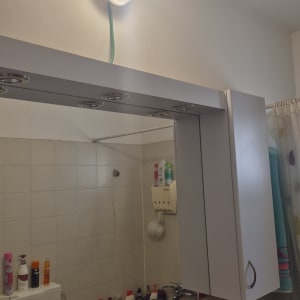 מנורה מותקנת על קיר בחדר אמבטיה עם מראה וארון