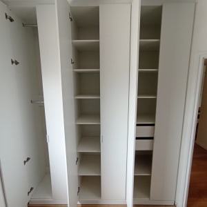 ארון בגדים לבן עם דלתות פתוחות ומדפים פנימיים