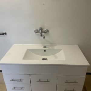 כיור לבן עם ברז על רקע קיר לבן