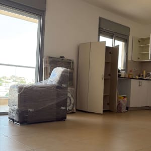 רהיטים עטופים בניילון בחדר ריק עם ארונות פתוחים