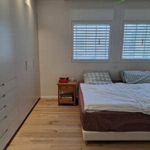 ארון בגדים לבן ליד מיטה זוגית עם כריות מנוקדות