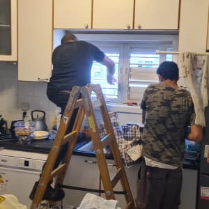 שני אנשים מתקנים תריס אלומיניום במטבח