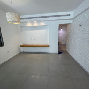 חדר עם קיר לבנים, מנורה ומטאטא בפינה