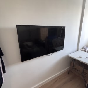 טלוויזיה מותקנת על קיר עם כבל חשמל גלוי