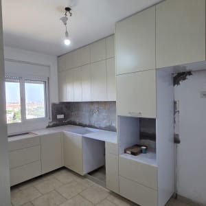 התקנת ארונות מטבח מודרניים בגוון בהיר במהלך שיפוץ דירה