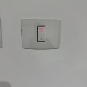 מתג חשמלי עם אור אדום על קיר לבן