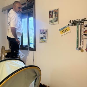אדם מתקן תריס ליד חלון בחדר עם קישוטים על הקיר