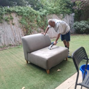 אדם מנקה ספה בחצר עם מכשיר ניקוי