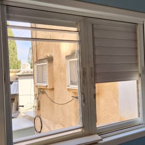 תריסים לבנים פתוחים וחלקית סגורים בחלון