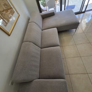 ספה אפורה ליד חלון זכוכית עם נוף לגינה