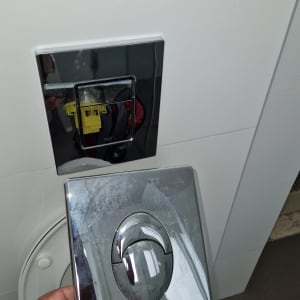 לחצן הדחה של אסלה עם כיסוי מונח בצד