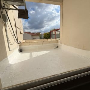 גג שטוח עם ציפוי לבן, צינורות חשמל וקיר בטון