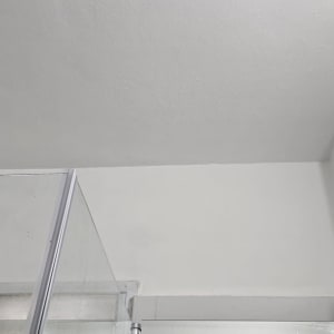 תקרה צבועה בלבן עם קיר זכוכית במקלחת