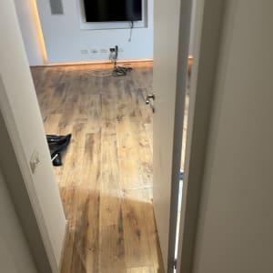 חדר עם רצפת עץ, טלוויזיה מותקנת על הקיר, חוטים חשמליים על הרצפה.