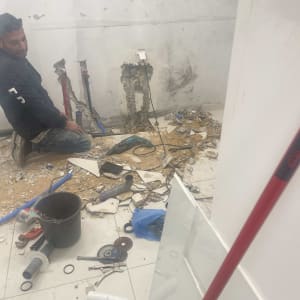 איש עם כלי עבודה בצנרת שבורה על רצפה