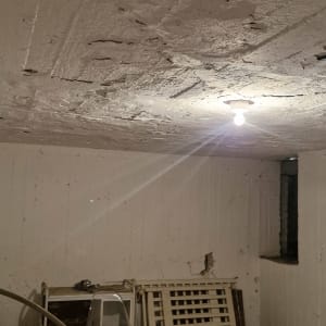 נורה תלויה מהתקרה בחדר עם קירות חשופים