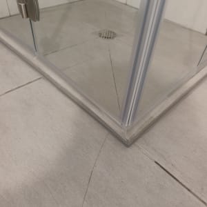 פינת מקלחון עם דלת זכוכית ורצפת אריחים
