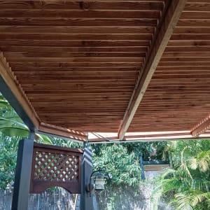 פרגולה מעץ עם קורות עץ חומות בגינה