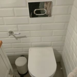 אסלה תלויה עם לחצן הדחה על קיר אריחים לבנים