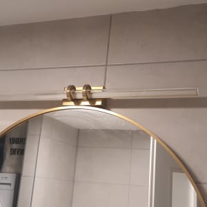 מנורת קיר מעל מראה עגולה בחדר אמבטיה