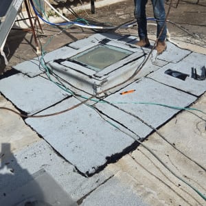 עבודת איטום על גג עם יריעות ביטומניות ואדם בעבודה