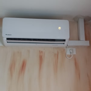 מזגן קיר לבן מותקן על קיר צבוע בצבעים שונים