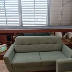 ספה ירוקה ליד חלון עם תריסים