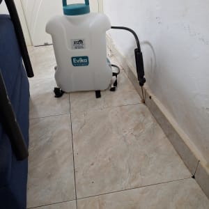 מיכל ריסוס לבן עם צינור שחור על רצפה