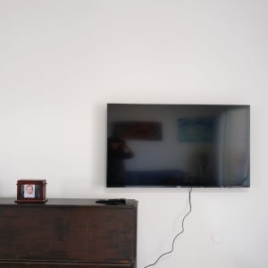 טלוויזיה תלויה על הקיר עם כבל חשמל גלוי