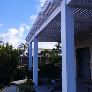 פרגולה מעץ לבן בגינה עם צמחייה ירוקה