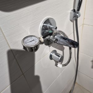 בדיקת לחץ מים באמצעות מד לחץ בחדר רחצה לאיתור נזילה