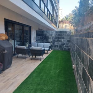 דשא סינתטי על שביל לצד קיר אבן