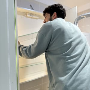 אדם מתקין מדף זכוכית בחדר אמבטיה