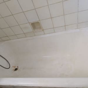 אמבטיה ישנה ומוכתמת עם חלודה סביב הניקוז לפני חידוש
