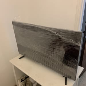 טלוויזיה עטופה בניילון על מדף לבן