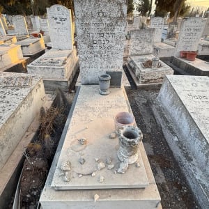 מצבת אבן ישנה בבית עלמין עם כיתוב מחרות ובית נר מאבן