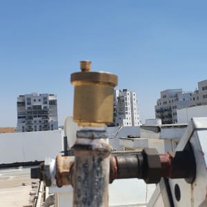 צינור מתכת עם שסתום על גג בניין