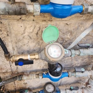 מד מים עם צינורות וברזים על קיר אבן