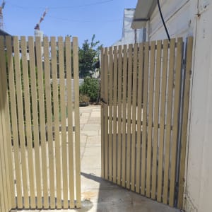 שער עץ פתוח בחצר עם שביל מרוצף