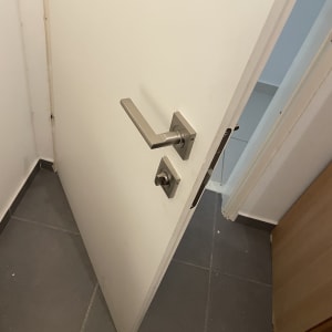 דלת לבנה פתוחה עם ידית מתכת מרובעת