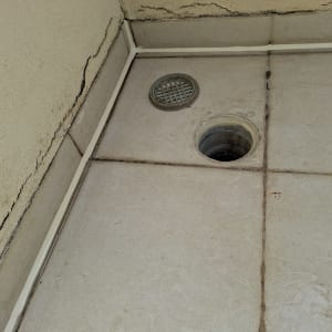 רצפה עם חור ניקוז וסדקים בקיר