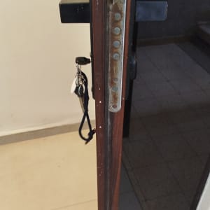 דלת כניסה פתוחה עם מנעול רב בריחי ומפתח בצילינדר