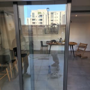 דלת זכוכית עם השתקפות של אדם ומבנה ברקע