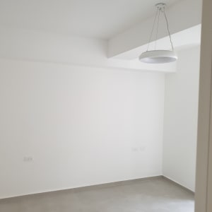 קיר לבן צבוע בחדר ריק עם מנורה תלויה